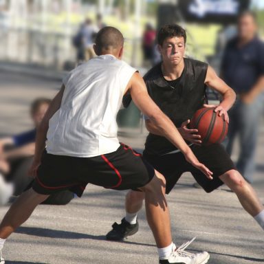 Deux joueurs de basketball en pleine action sur un terrain extérieur.